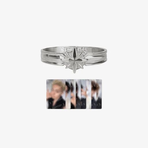 A silver-toned band ring with a starburst or compass-like emblem on the front, shown above a small vertical collage of blurred portrait photos. The ring appears metallic silver with engraved text inside the band.